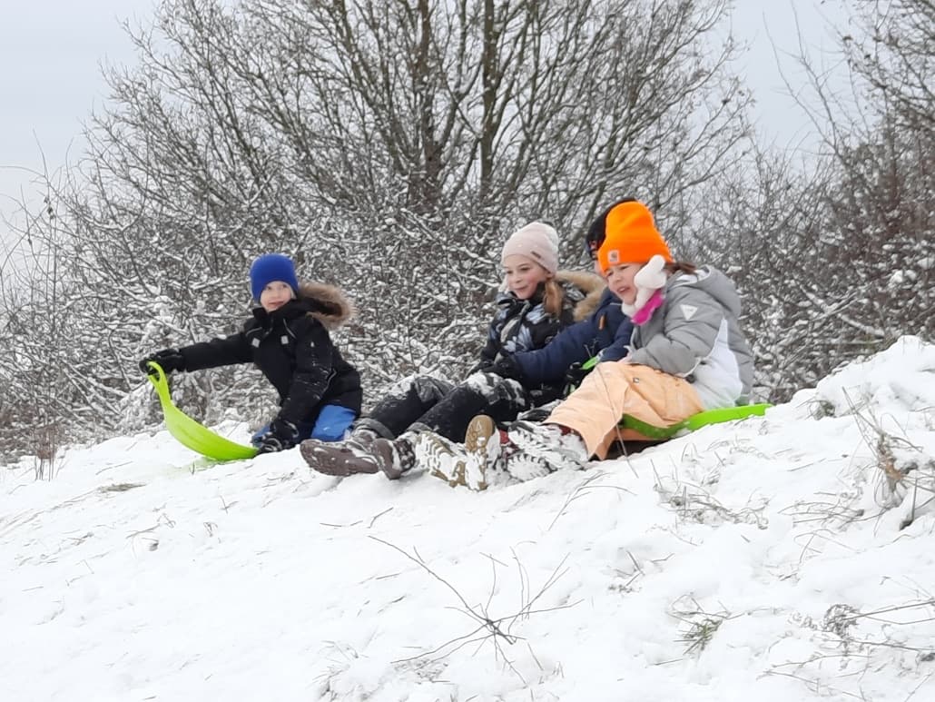 Kinder rodeln im Schnee einen Hang hinunter